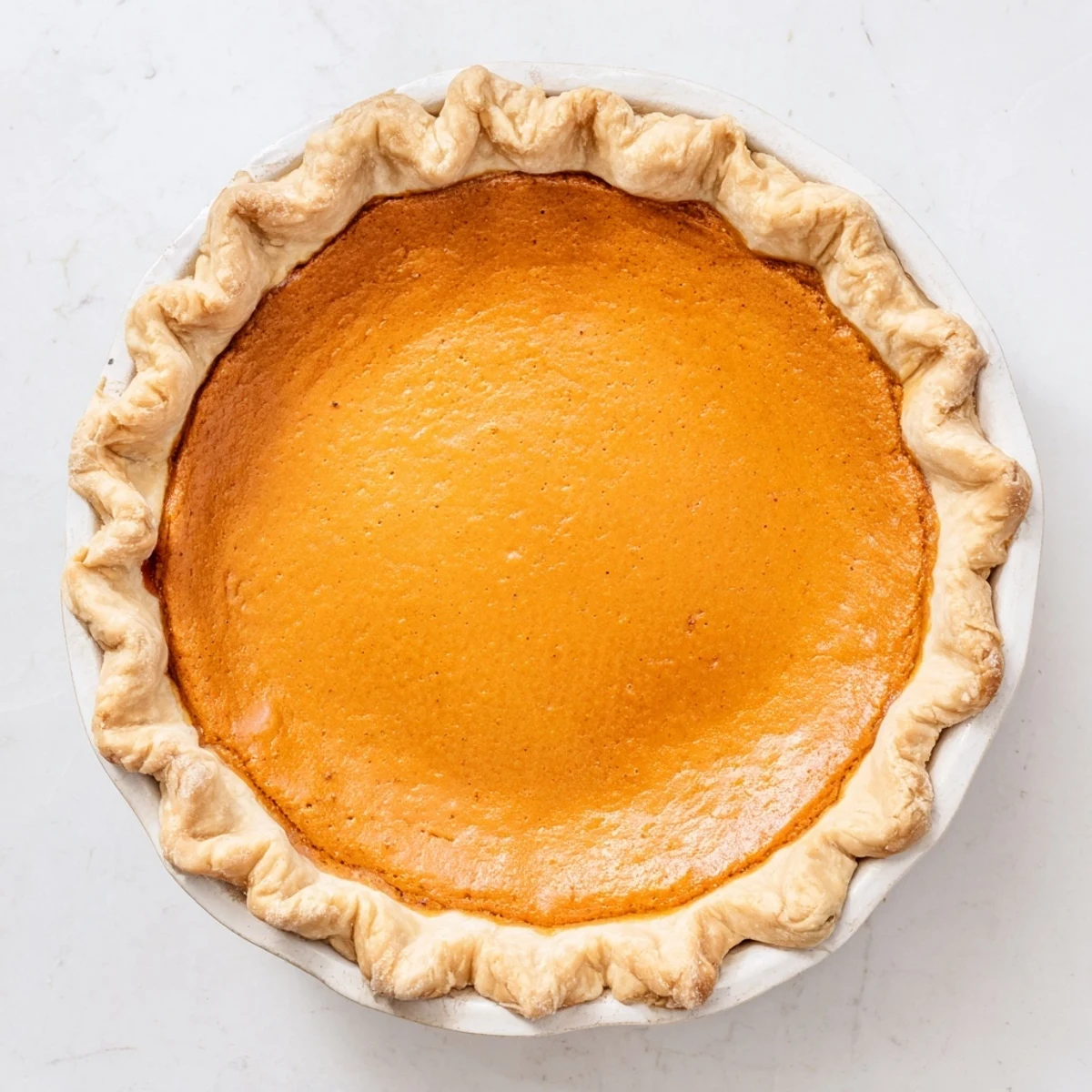 Homemade Pumpkin Pie cooling on a rack, showcasing a perfectly crimped edge and rich orange hue.