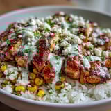Creamy zesty crema drizzled over Street Corn Chicken and Rice Bowls, garnished with crumbled cotija and fresh cilantro.