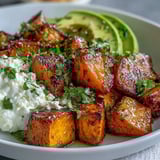 Golden roasted sweet potatoes mingle with fresh avocado slices and a scoop of cottage cheese in this vibrant bowl. The spicy-sweet hot honey glaze adds a glossy finish for a comforting meal.