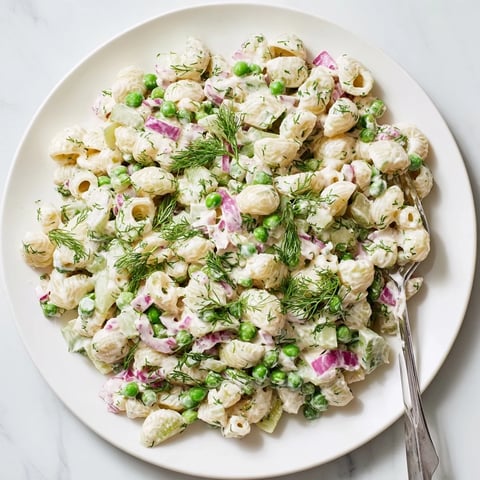 A close-up of Creamy Dill Pickle Pasta Salad with ditalini, peas, and diced pickles in a zesty dressing.  