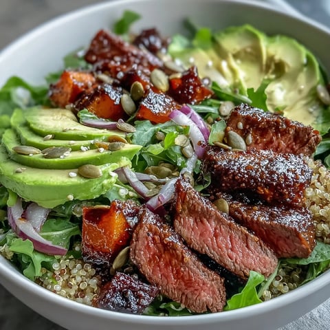 Golden-brown roasted butternut squash steak bowls are piled high over fluffy quinoa and greens, topped with avocado and pepitas.