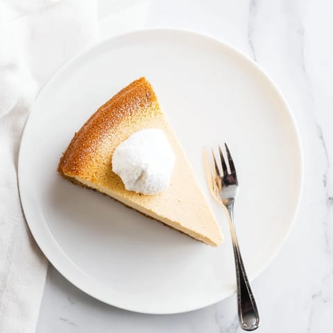 A whole New York Cheesecake cooling on a rack with visible steam, highlighting its creamy texture.