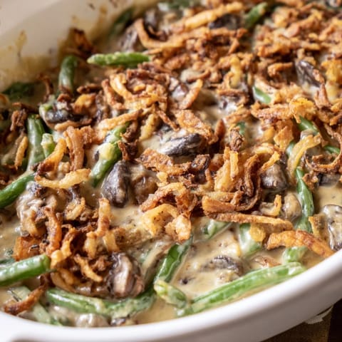 Tender green beans coated in a rich, savory sauce topped with golden crispy onions for a classic American side.
