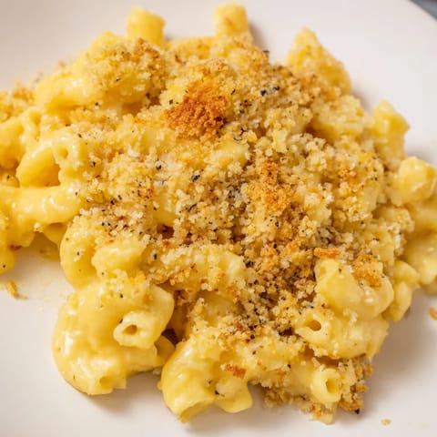 Creamy cheddar cheese sauce coats tender macaroni, served as a comforting side dish on a rustic plate.