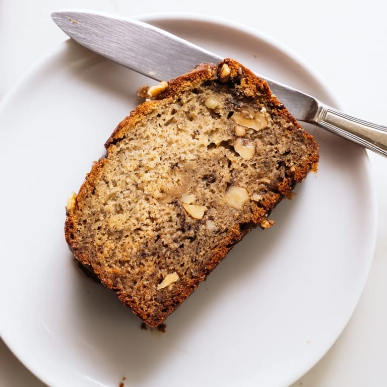 Slices of moist Banana Bread topped with a melting pat of butter, paired with a steaming mug of coffee for breakfast.