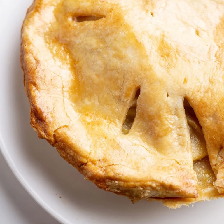 Freshly baked Chicken Pot Pie in a glass dish, featuring visible peas, carrots, and tender chicken chunks.