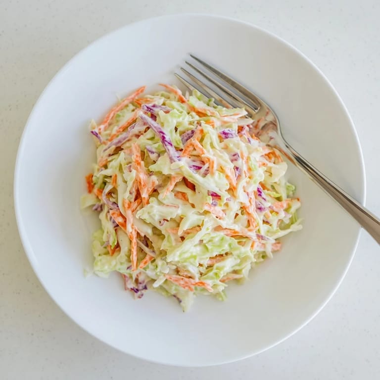 A chilled bowl of homemade Coleslaw, perfect for serving alongside smoky barbecue ribs or a juicy pulled pork sandwich.