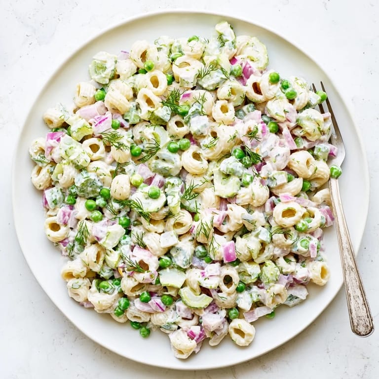 A picnic-style serving of Creamy Dill Pickle Pasta Salad alongside grilled chicken and crusty bread.
