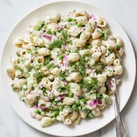 A close-up of Creamy Dill Pickle Pasta Salad with ditalini, peas, and diced pickles in a zesty dressing.  